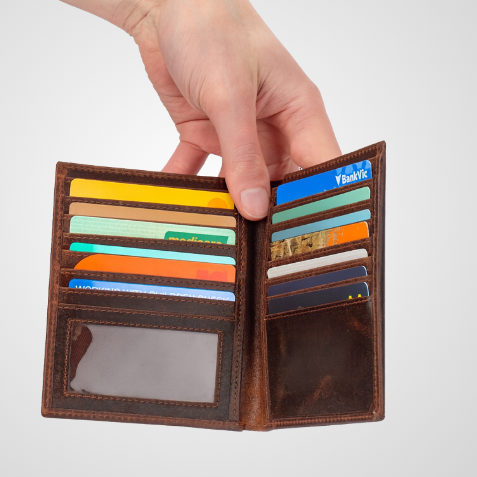 Hand holding a brown leather wallet with colorful cards against a light gray background